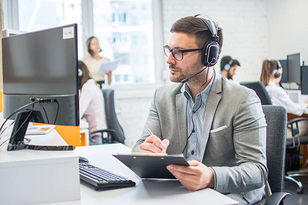 businessman checking data from computer and writing it to clipboard.